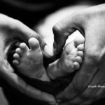 Woman's hand around baby's feet