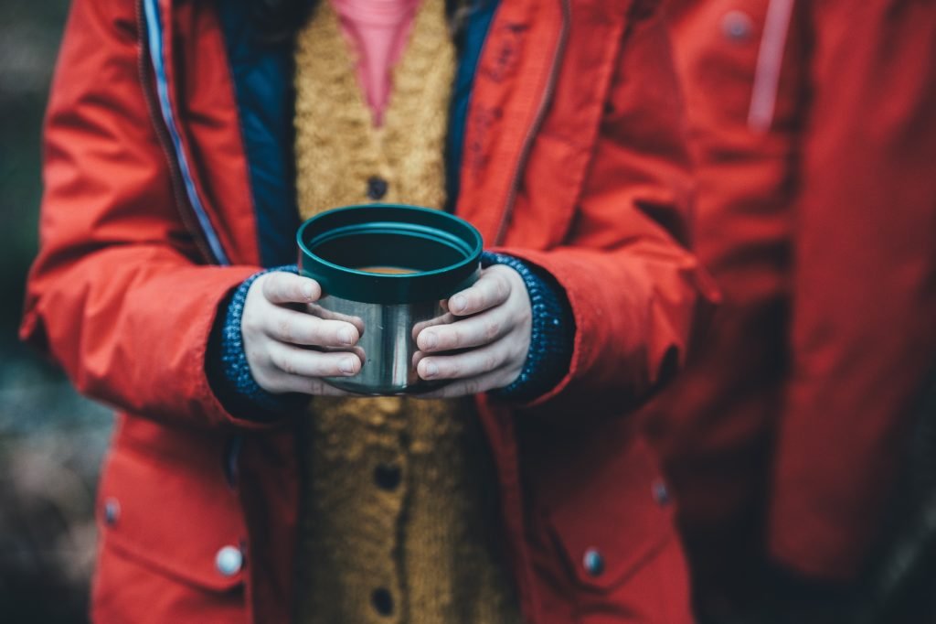 Person in coat holding mug