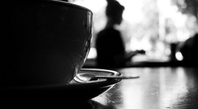 Coffee cup with woman in background, black and white