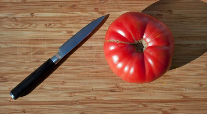Photo of a ripe tomato with a knife beside it