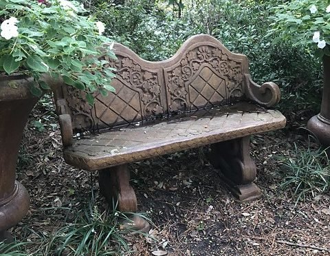 Color photo of ornate stone bench in a garden