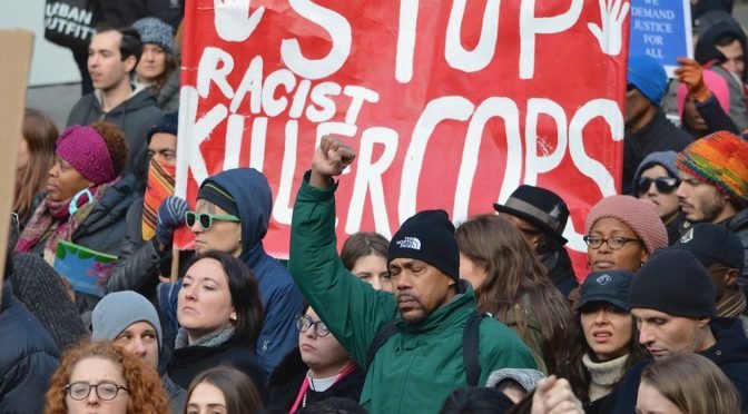 Photo of marchers holding Stop Racist Killer Cops sign
