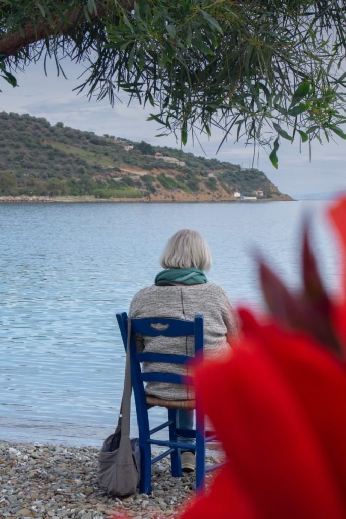 Photo of woman sitting in chair facing water