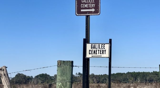 Dusty terrain, fence post reading Gallilee Cemetery