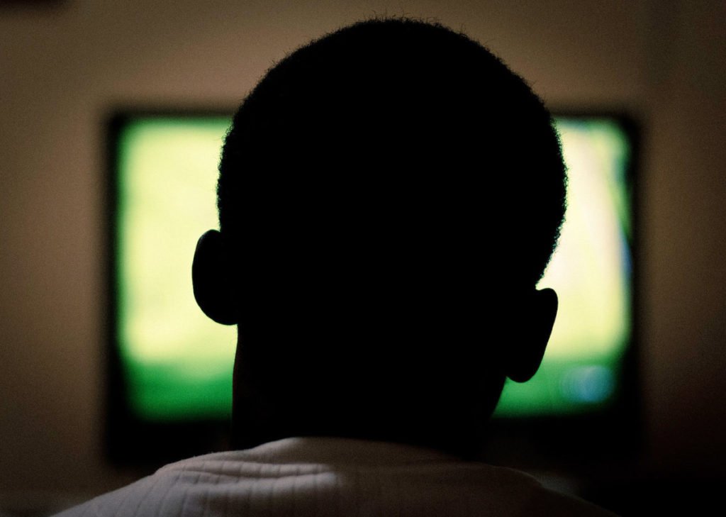 Silhouette of man's head in front of tv
