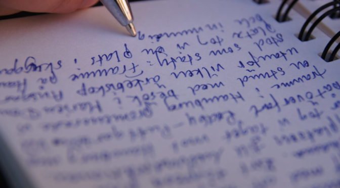 Photo of pen writing in notebook