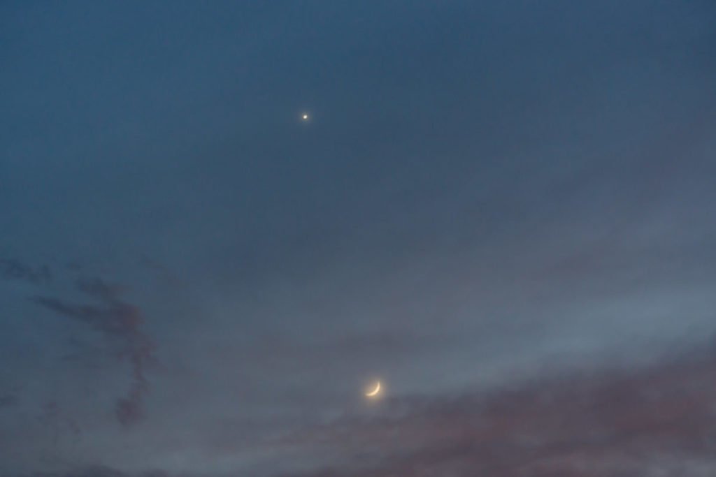 crescent moon and venus in pale blue sky