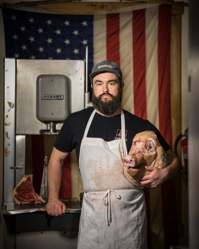 Man holding pig head in front of American flag