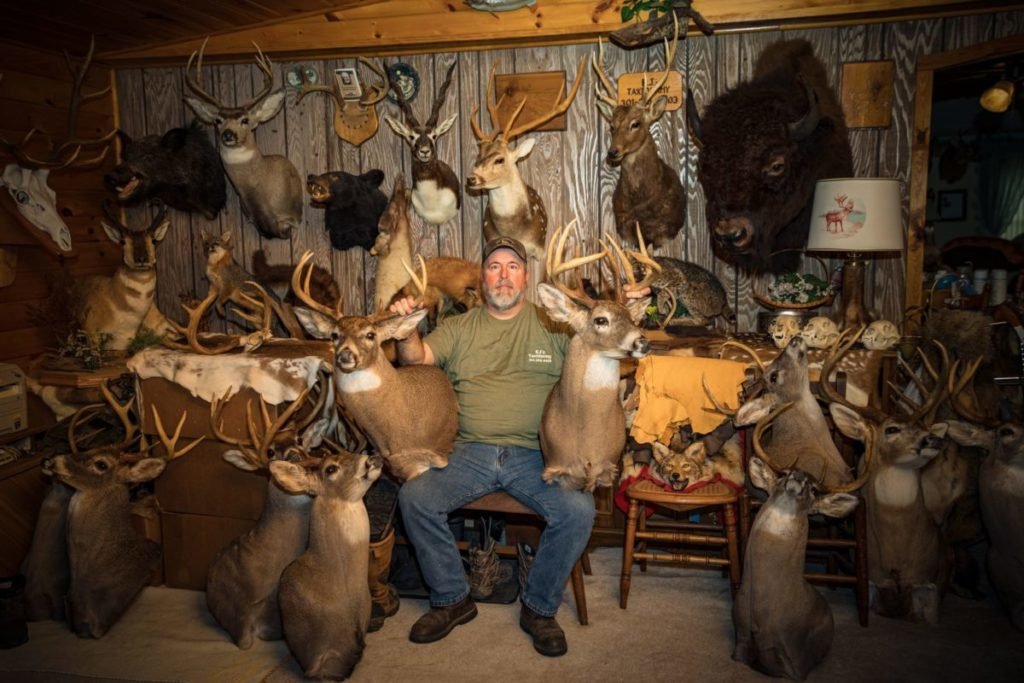 Man surrounded by stuffed deer heads