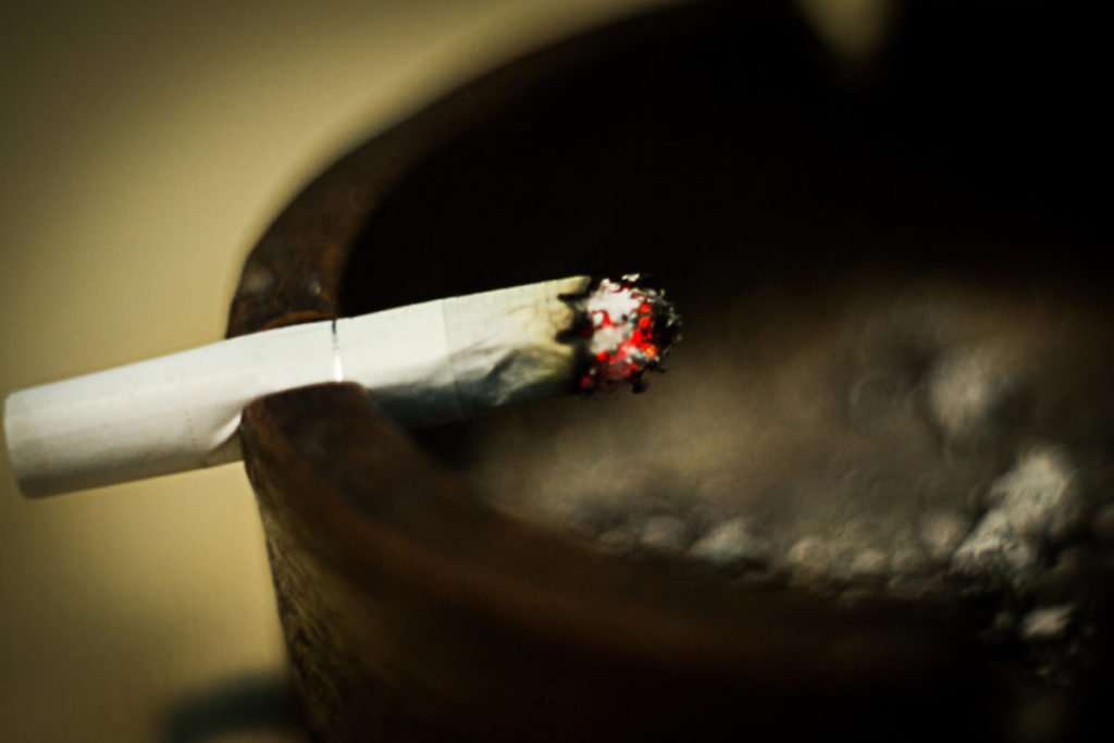 Photo of lit cigarette resting against ashtray