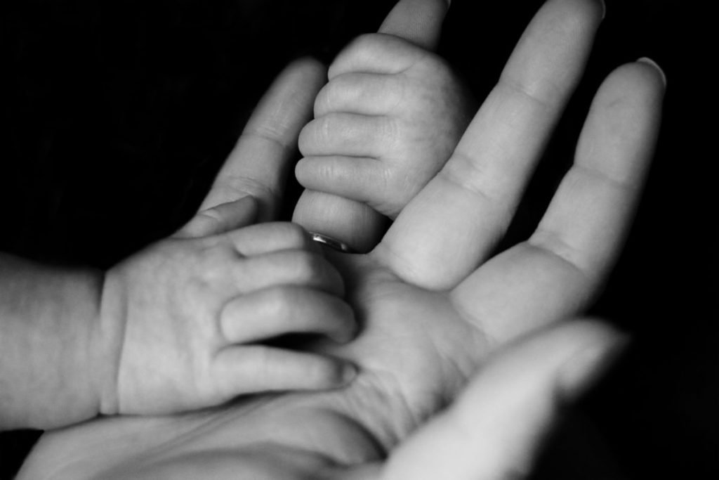 Black and white photo of baby hands holding adult hand