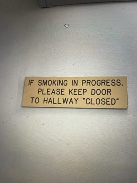 Photo of sign that says: If Smoking in Progress, Please Keep Door to Hallway "Closed"