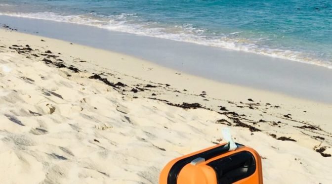 Photo of orange suitcase on beach
