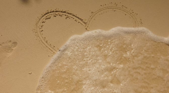 Photo of heart drawn in sand washing away