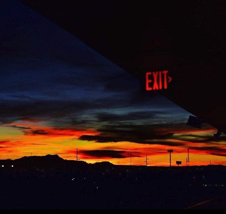 Photo of exit sign in front of orange/red/blue sunset