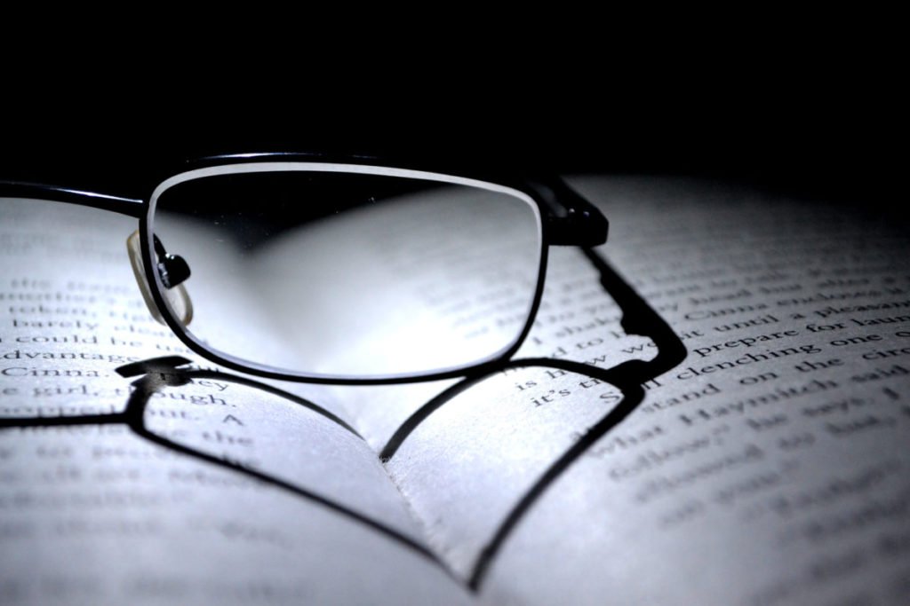 Black and white photo of glasses on open book