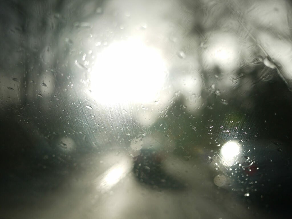 rainy window with large white light on road