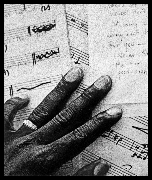 Photo of black hand holding sheet music
