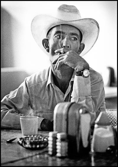 Black and white photo of man in cowboy hat smoking