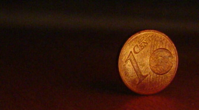 coppery coin with numeral one on it against black background