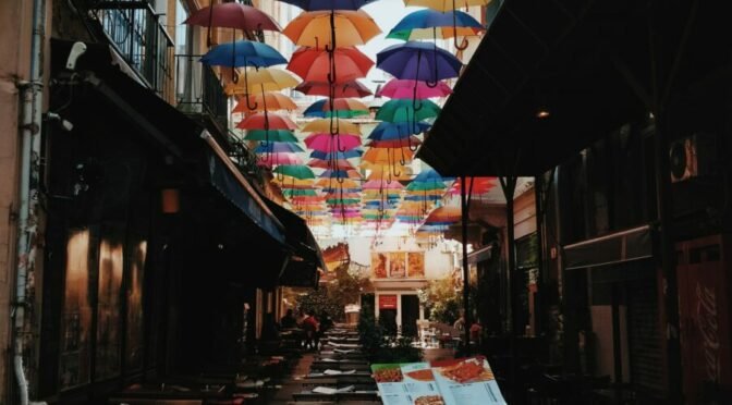 Photo of colorful umbrellas above dining tables in alley