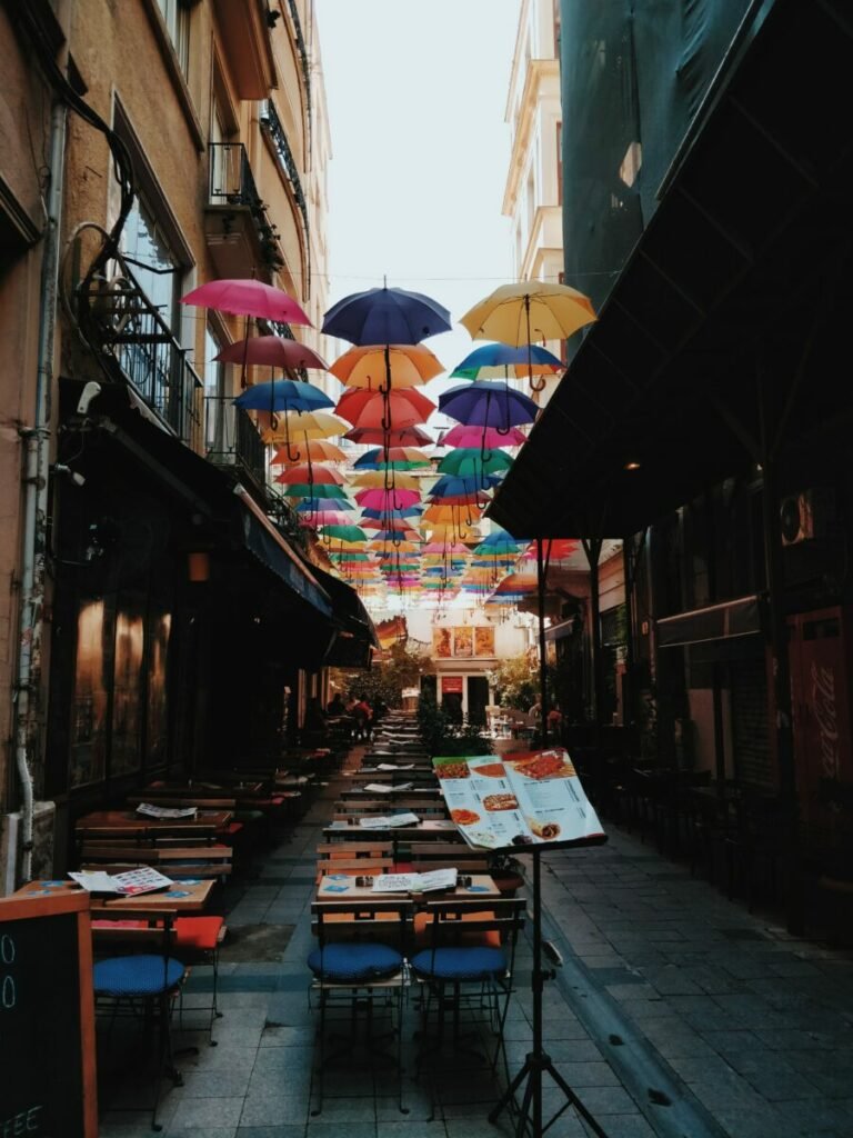 Photo of colorful umbrellas above dining tables in alley