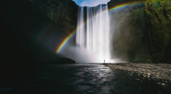Photo of waterfall with rainbow through it
