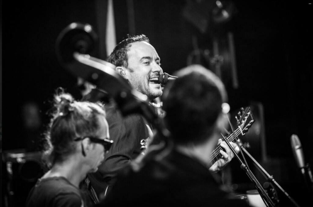 Black and white photo of Dave Matthews singing and playing guitar
