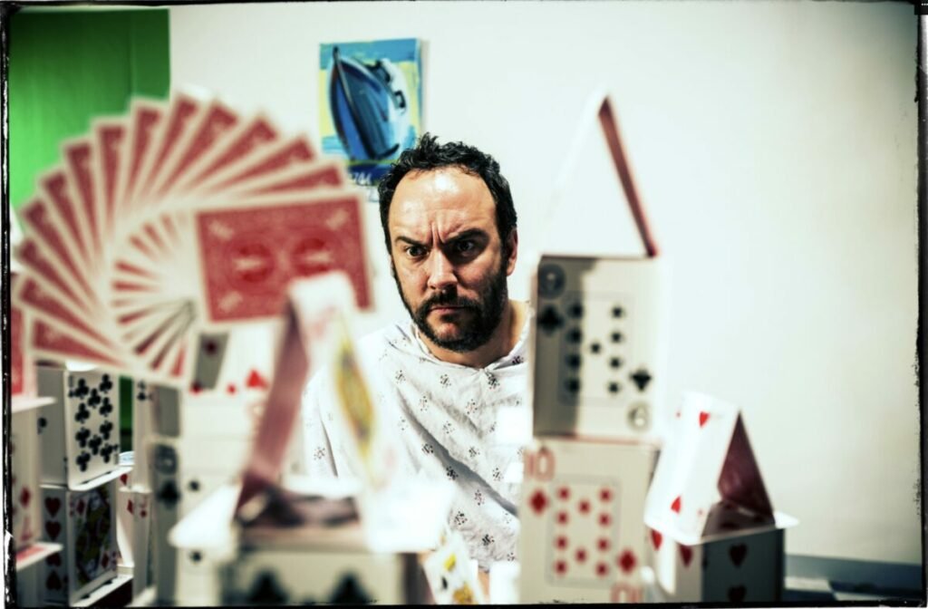Photo of Dave Matthews with cards built into towers in front of him