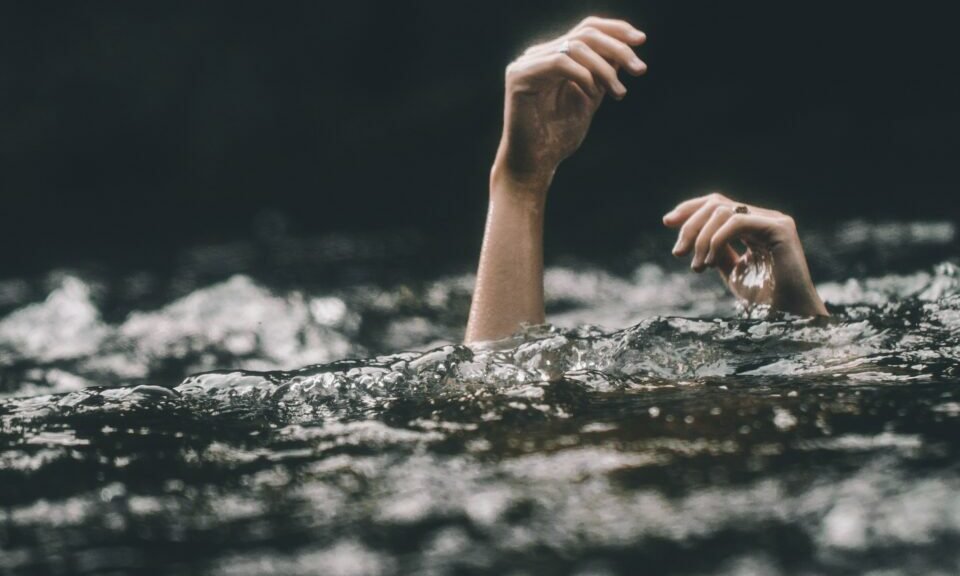 Photo of hands sticking up through water