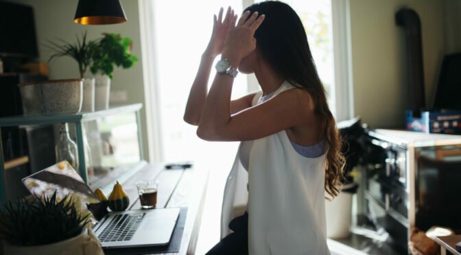 Photo of woman throwing hands in air while looking at computer