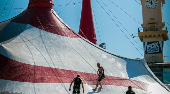 Photo of people walking on top of a red and white circus tent