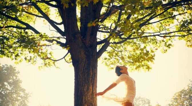woman in white leotard mid-air beneath autumn tree