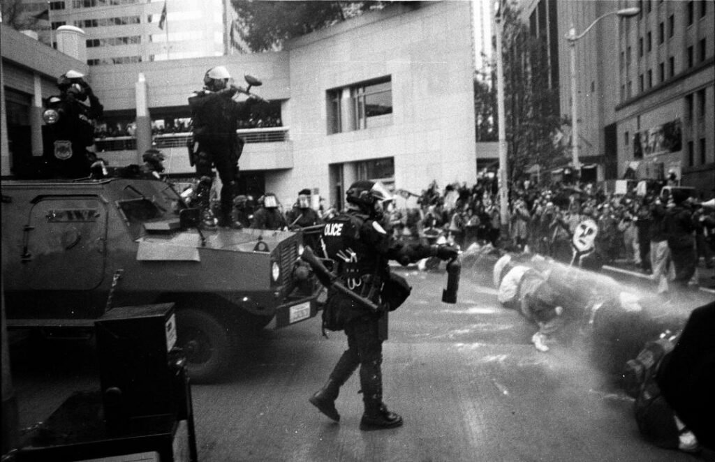 Black and white photo of armed police facing protesters 