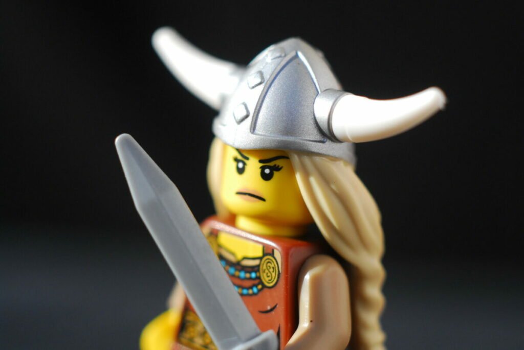 Close up photo of frowning Lego woman with viking hat, long braided hair, and sword