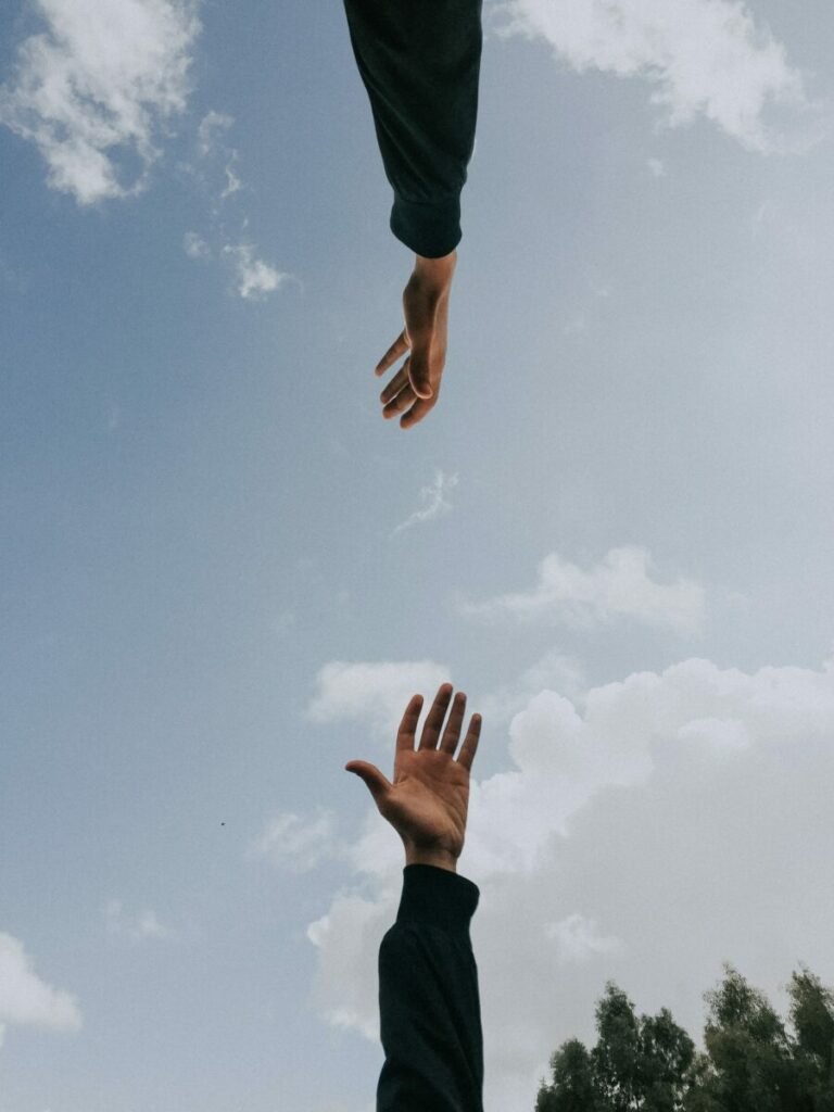 hand reaching up, another reaching down, blue sky background