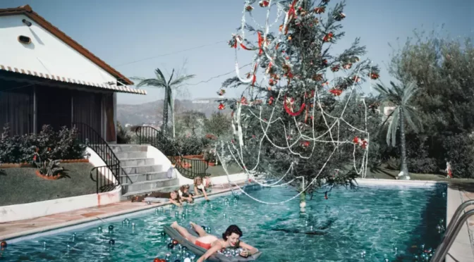 Photo of woman in pool in front of decorated Christmas tree