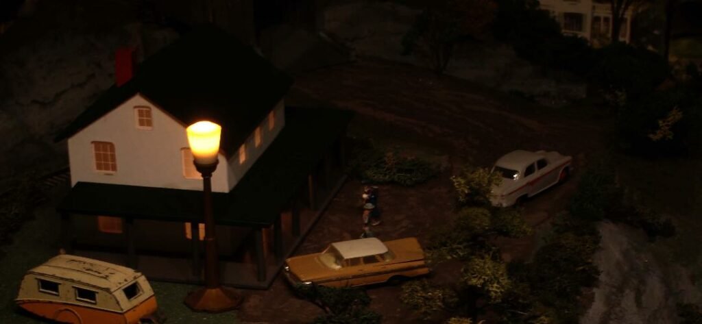 Photo of model town at night, with a house, streetlight, and cars