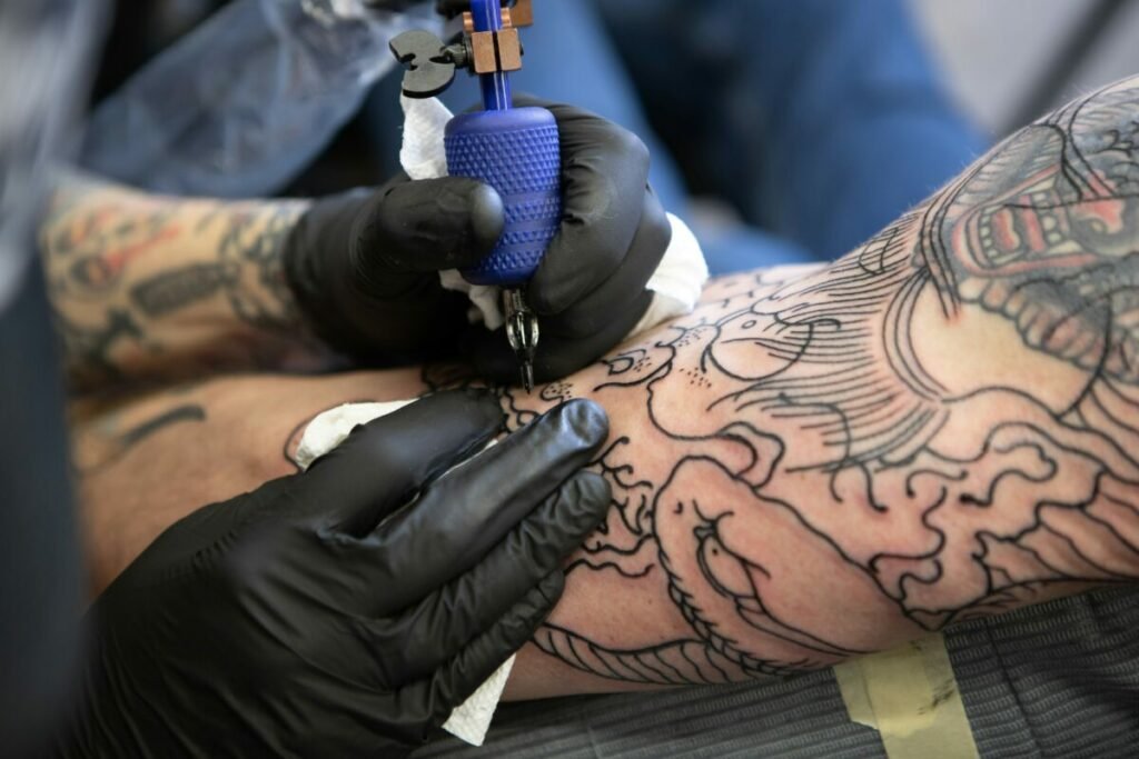 Photo of pair of hands tattoing someone's arm