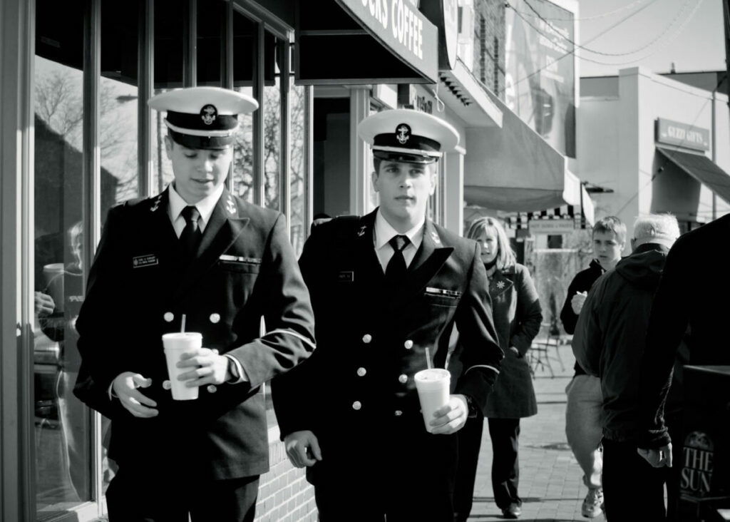 Black and white pic of two naval men in uniform, walking down street