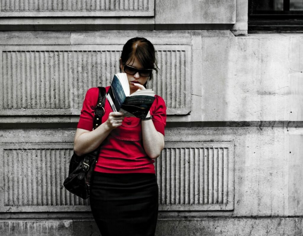 Woman standing against wall, reading