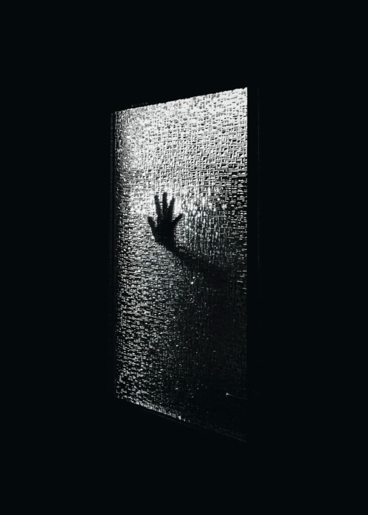 Black and white photo of hand seen through frosted glass