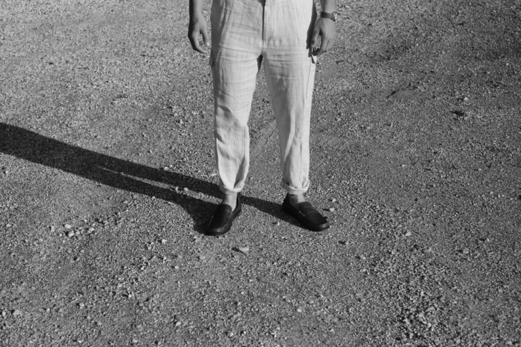 grey tones, lower half of man's body standing on gravel