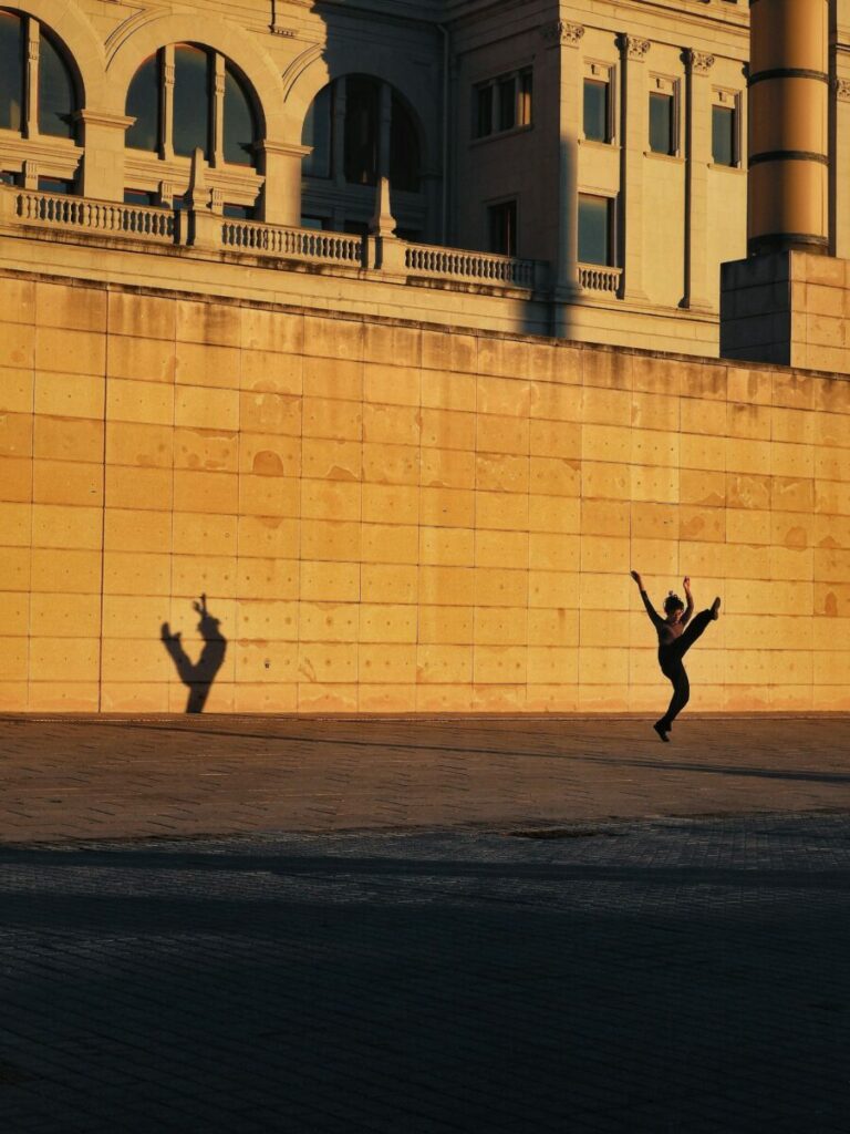 dancer and shadow cast on gold building at night