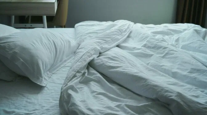 rumpled white bed in dim light