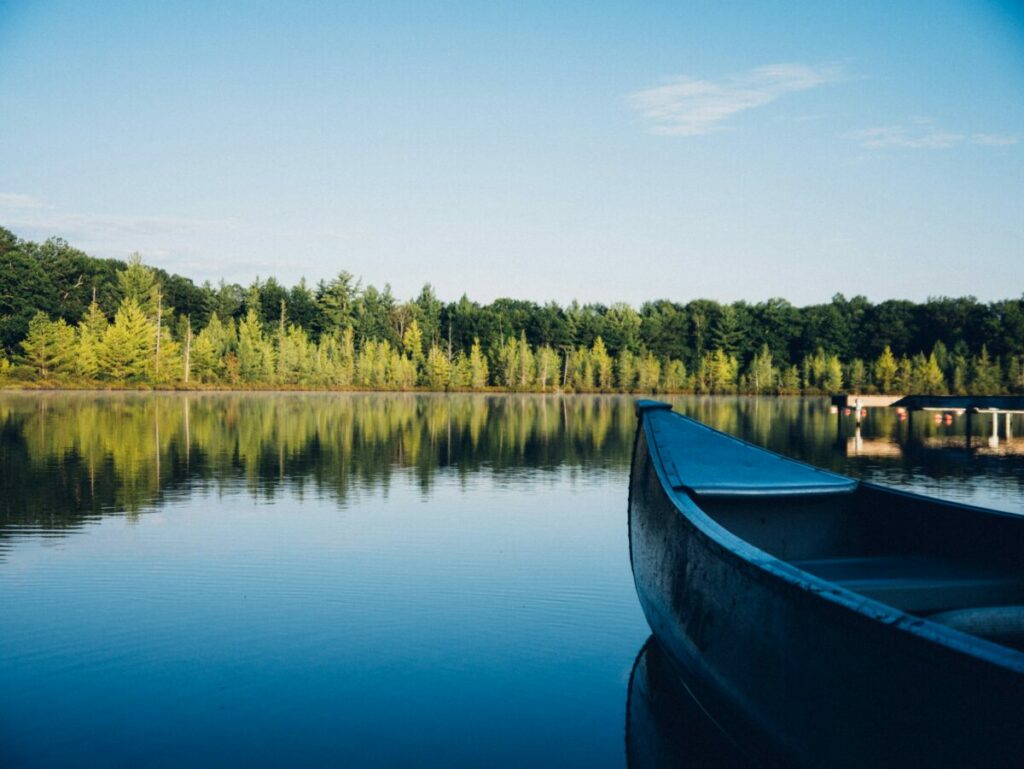 Photo of front of canoe on water, with forest in background