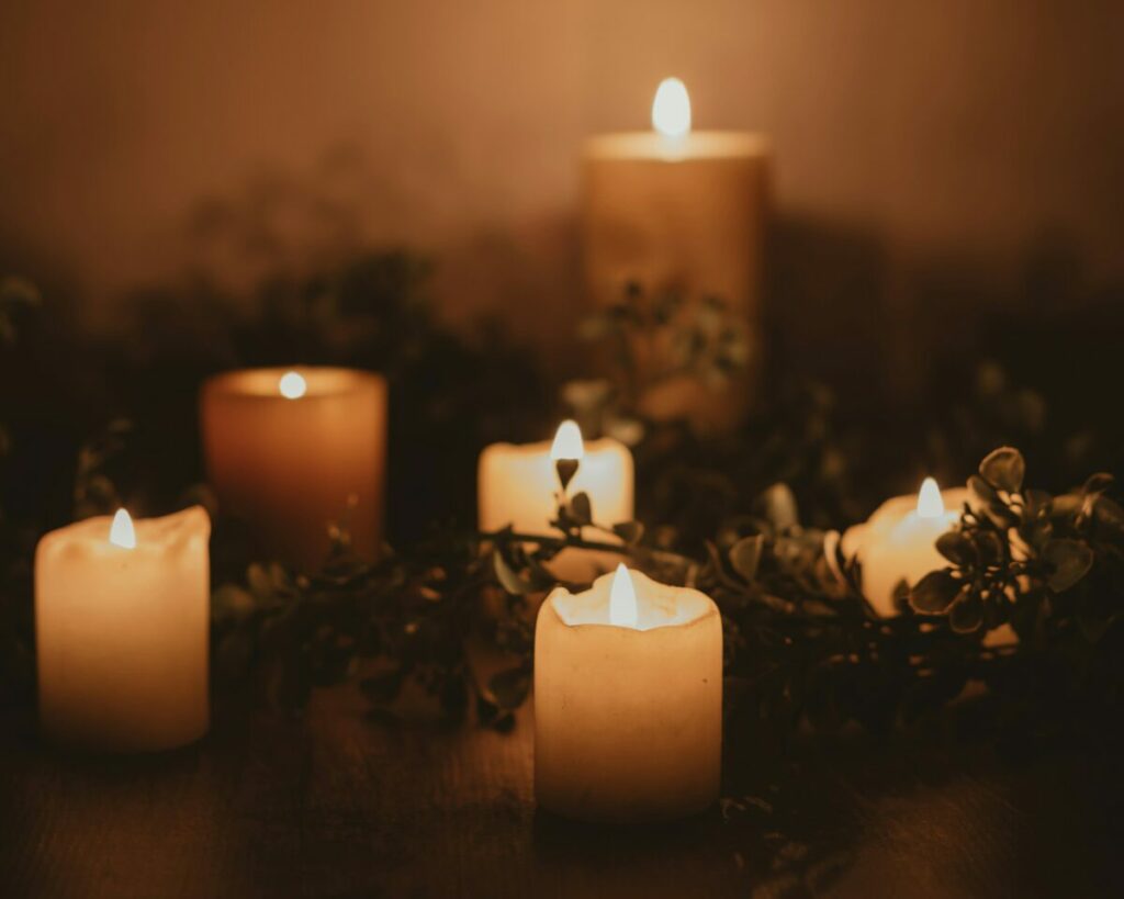 Photo of lit candles with greenery around them