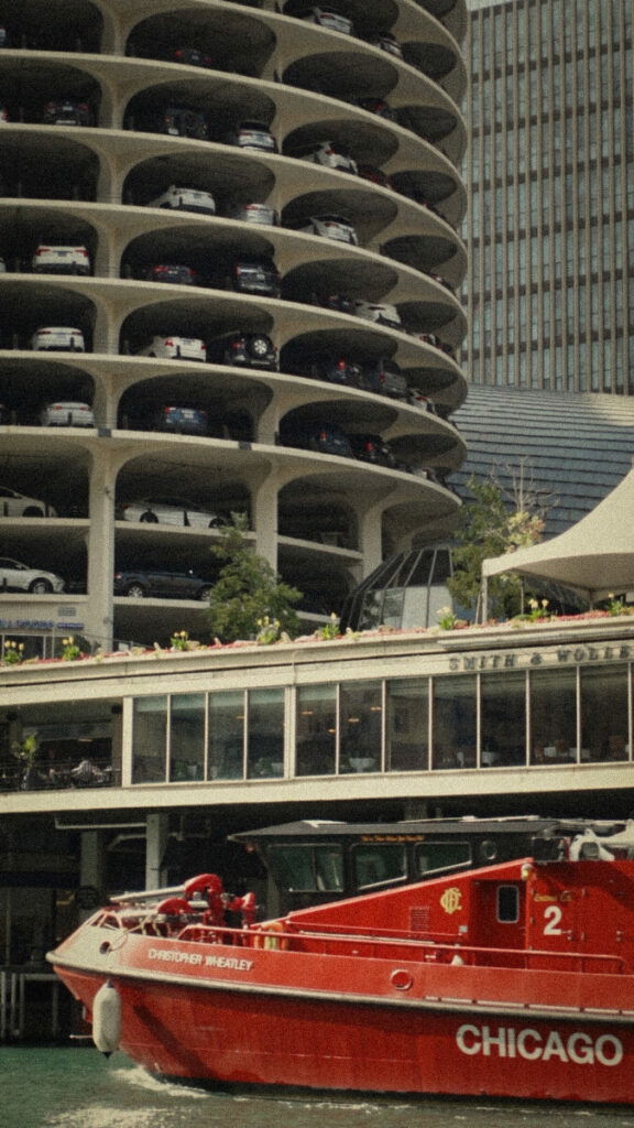 Photo of red boat that say s Chicago in front of parking deck and pier