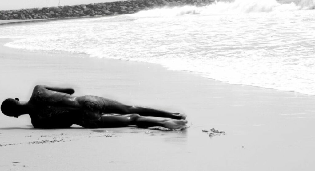 Black and white photo of body laying on beach