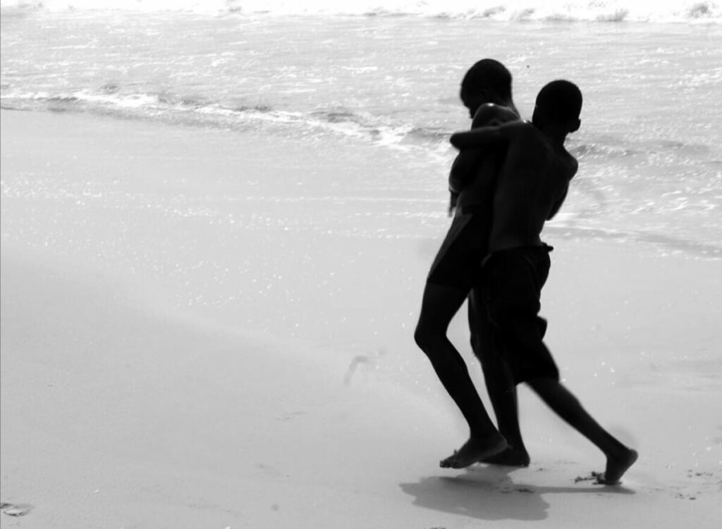 Black and white photo of two boys playing on beach